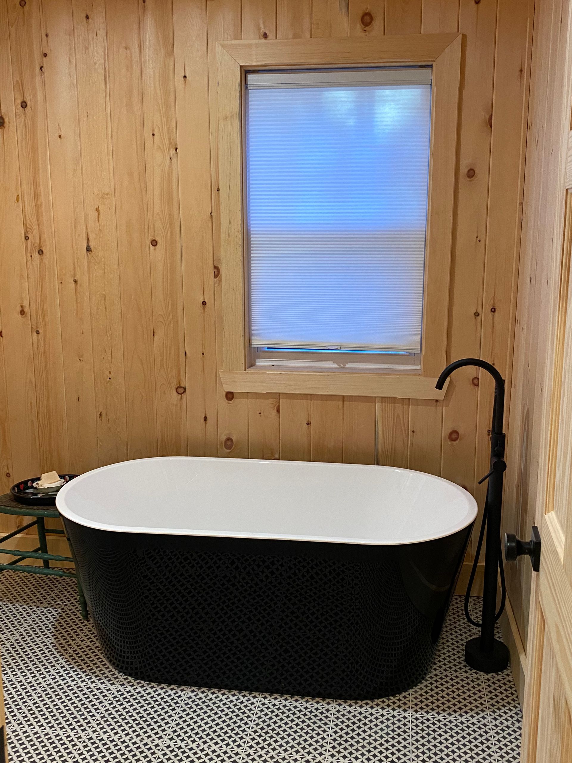 A black bathtub is sitting in a bathroom next to a window.