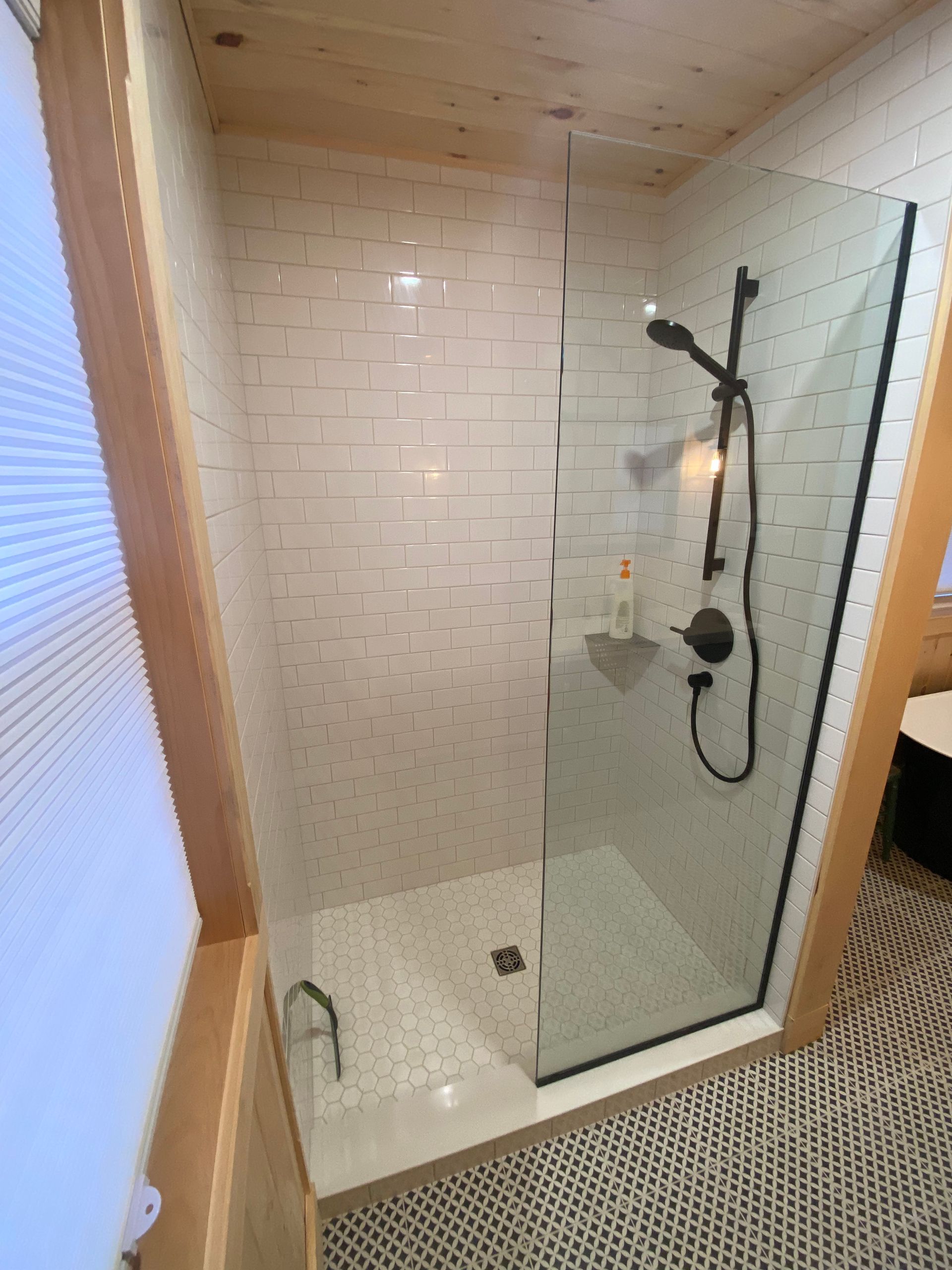 A bathroom with a walk in shower with a glass door.