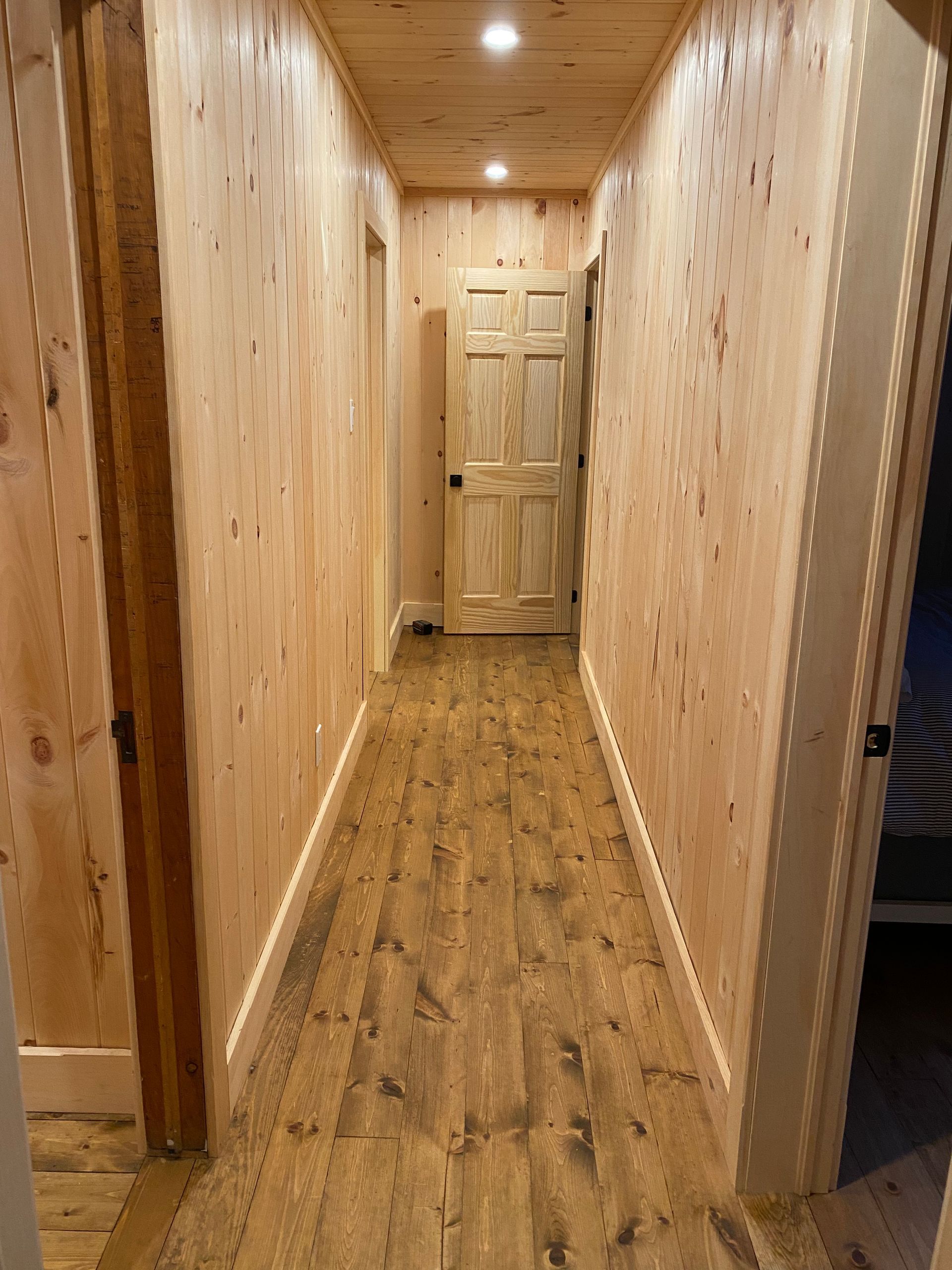 A long hallway with wooden floors and doors in a house.