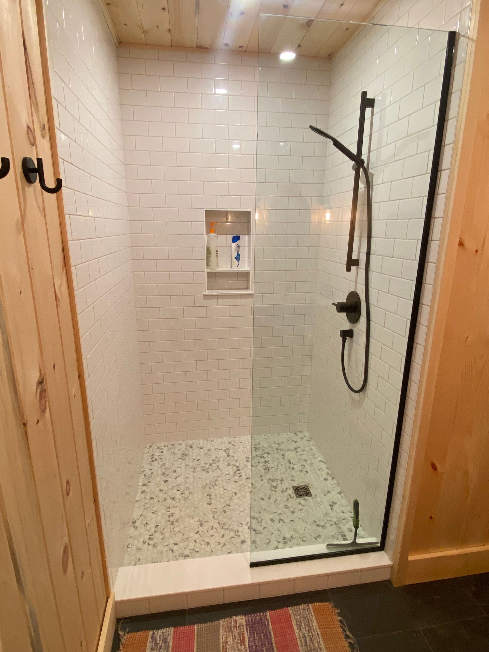 A bathroom with a walk in shower with a glass door.