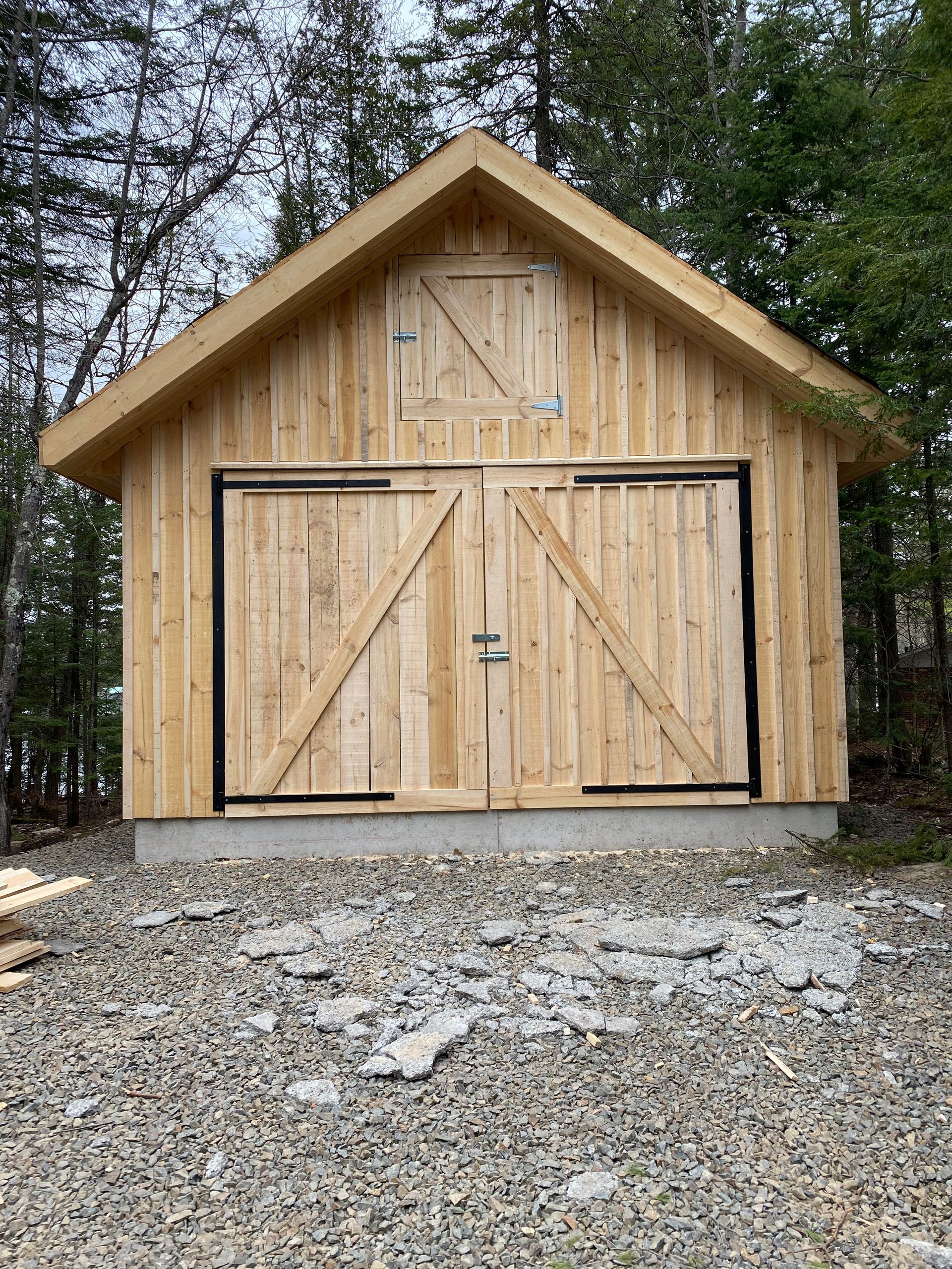 A wooden garage is sitting on top of a gravel lot.