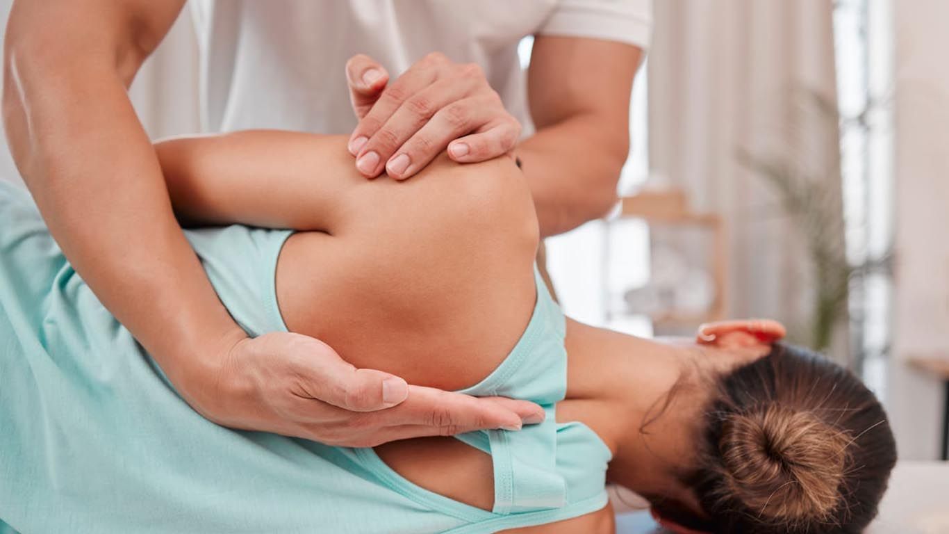 A man is giving a woman a physiotherapy on her back.