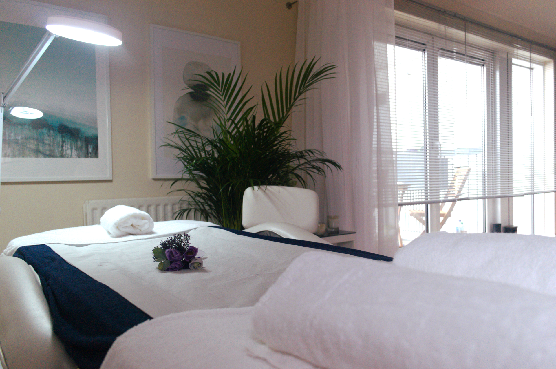 Massage bed with white sheets and purple flower