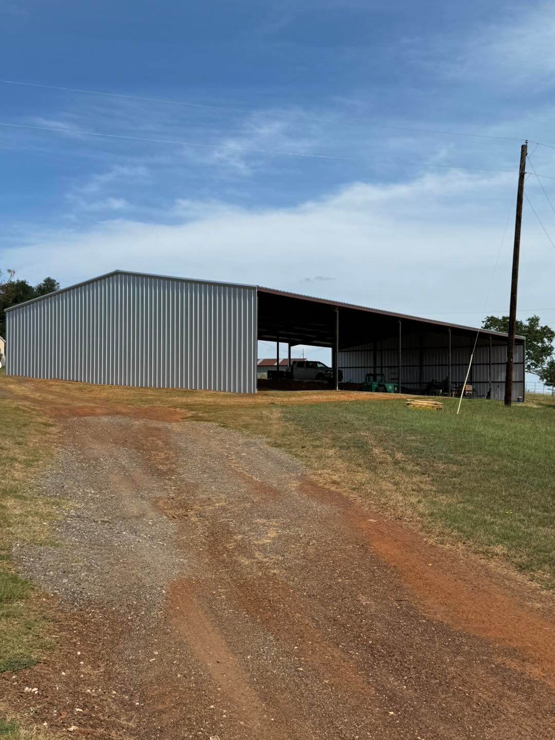 A large metal building is sitting in the middle of a dirt road.