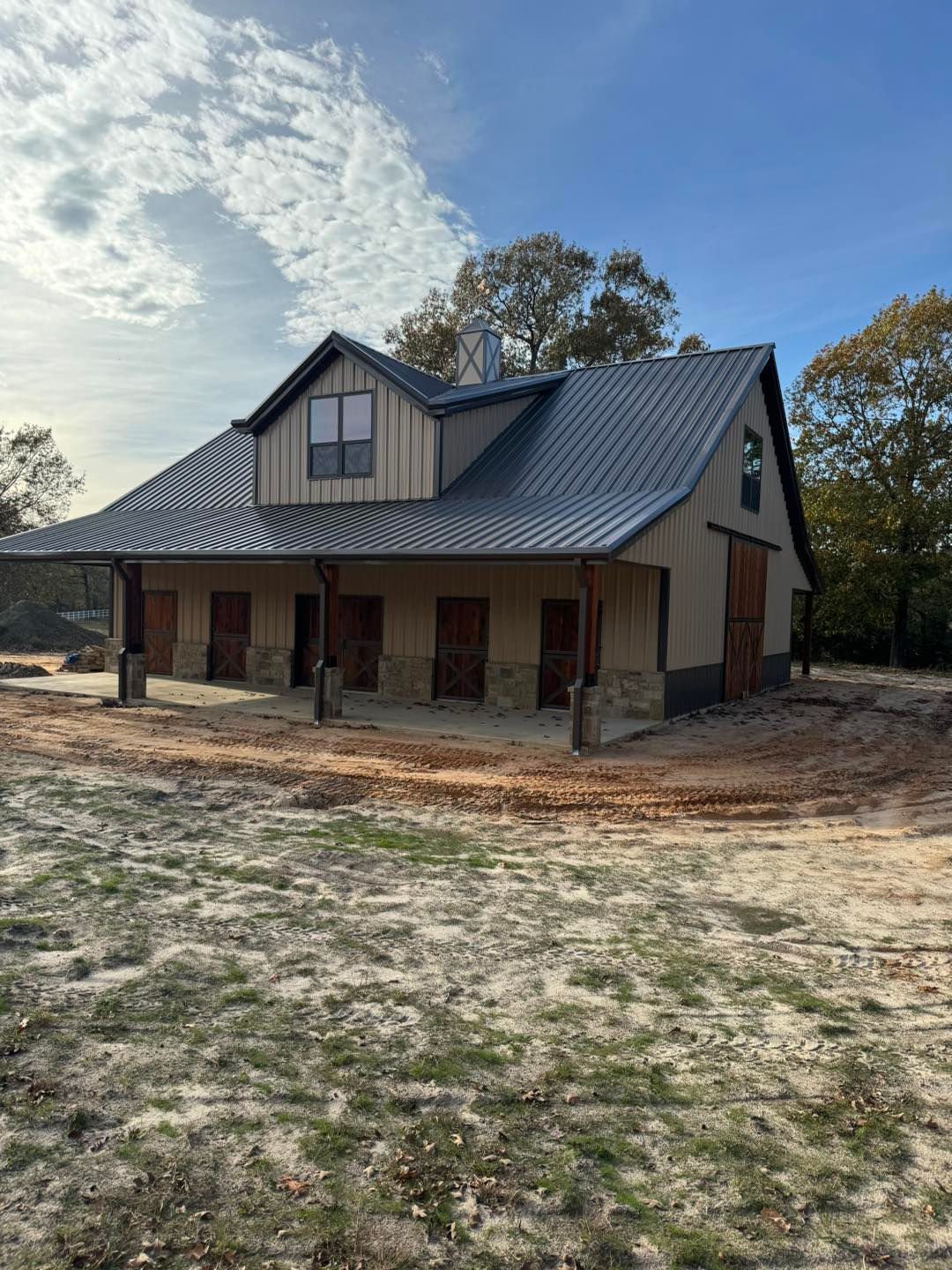 A large house with a metal roof is sitting in the middle of a dirt field.