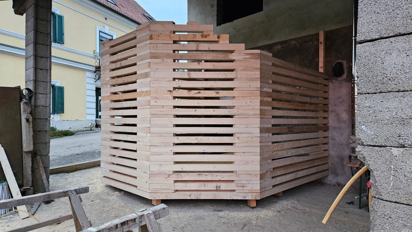 Vor einem Gebäude wird eine Holzkonstruktion errichtet.