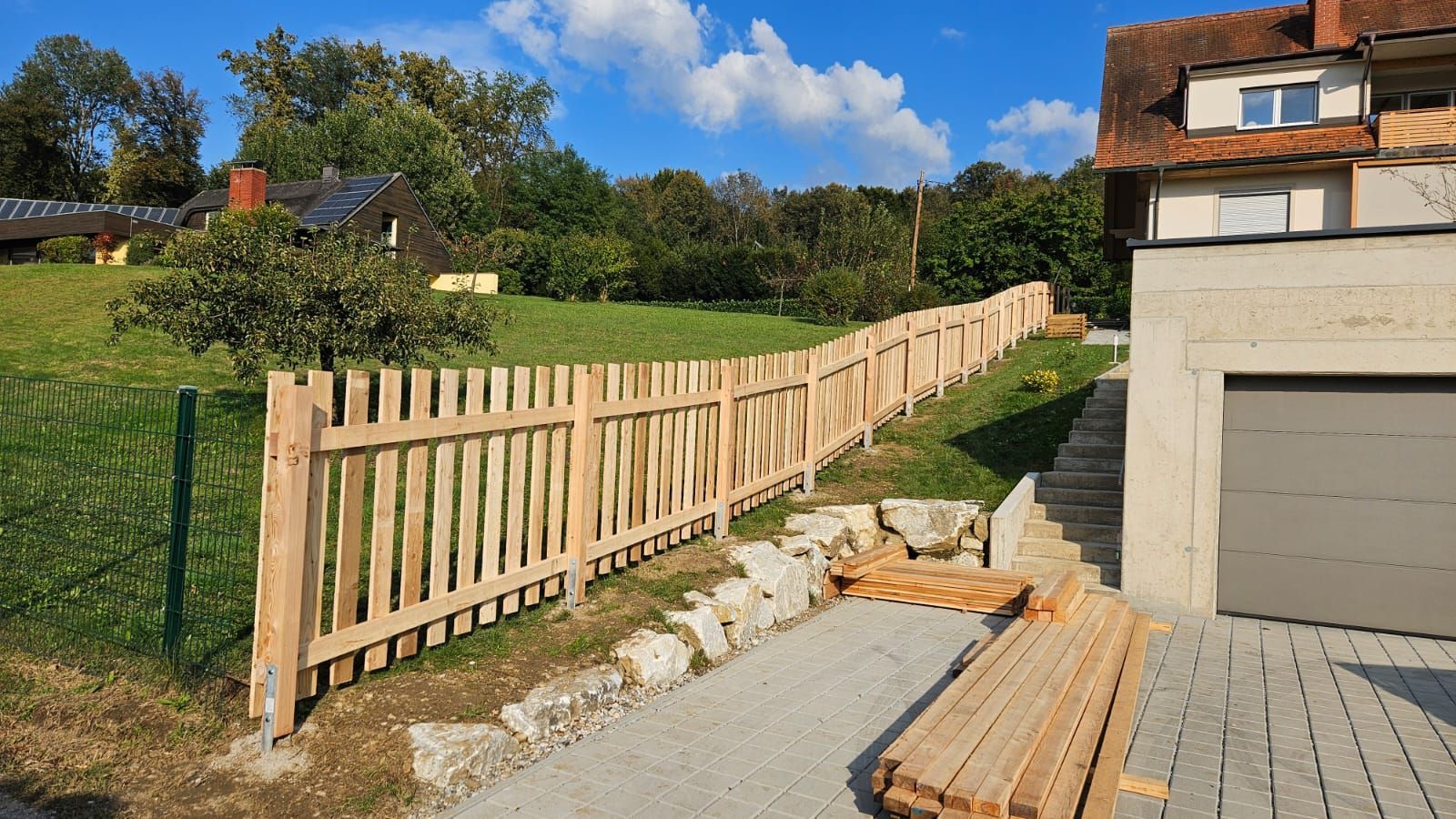 Vor einem Haus wird ein Holzzaun gebaut.