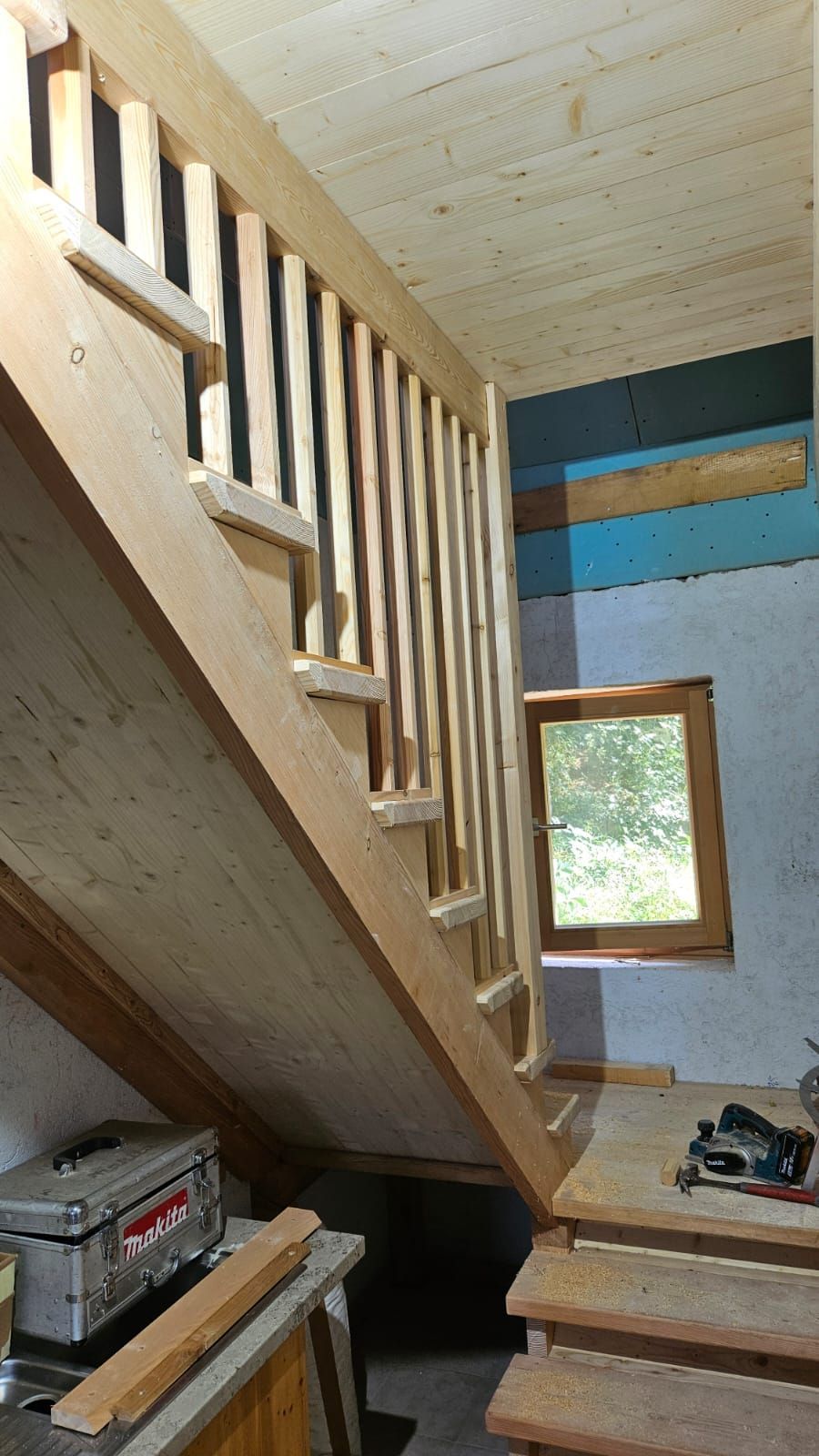 In einem Raum mit Fenster wird eine Holztreppe gebaut.