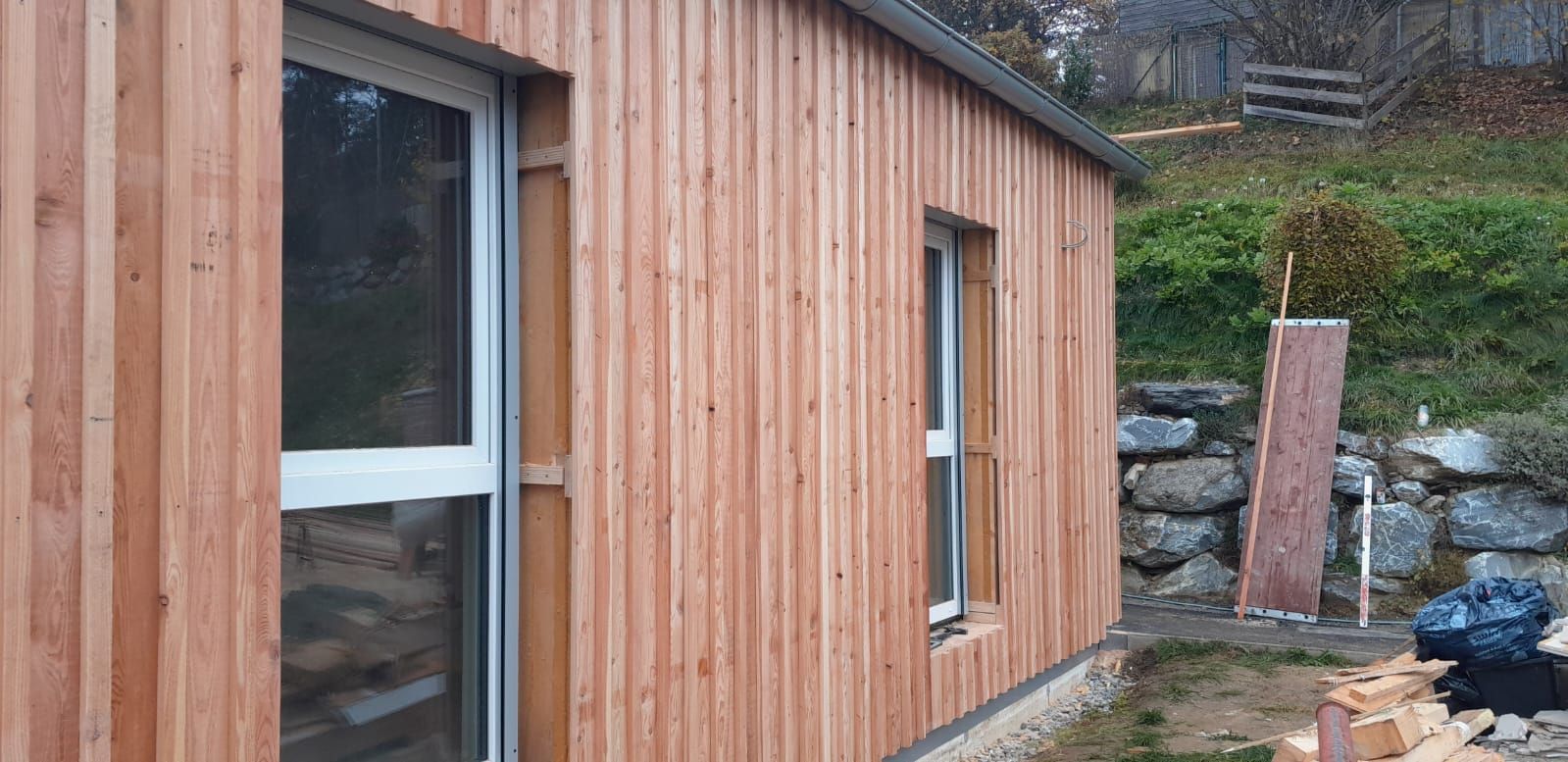 Ein Holzhaus mit zwei Fenstern und einer Glasschiebetür.