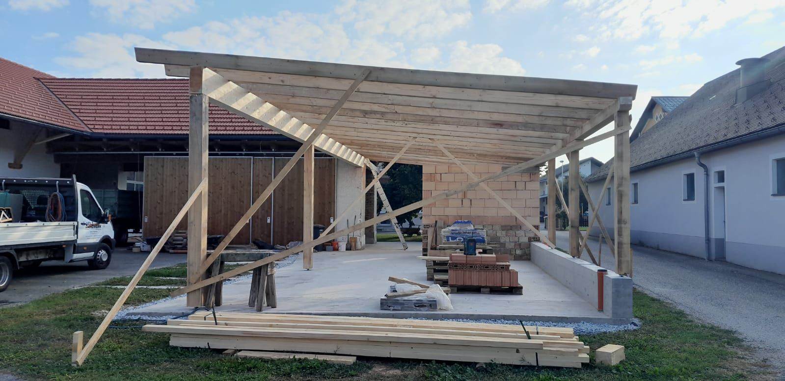 Vor einem Haus wird eine Holzkonstruktion errichtet.