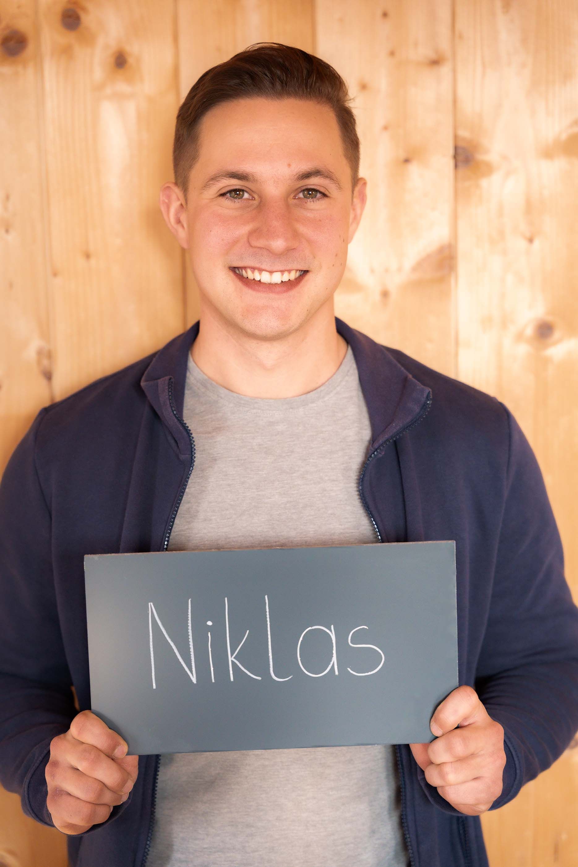Ein junger Mann hält ein Schild mit der Aufschrift „Niklas“.