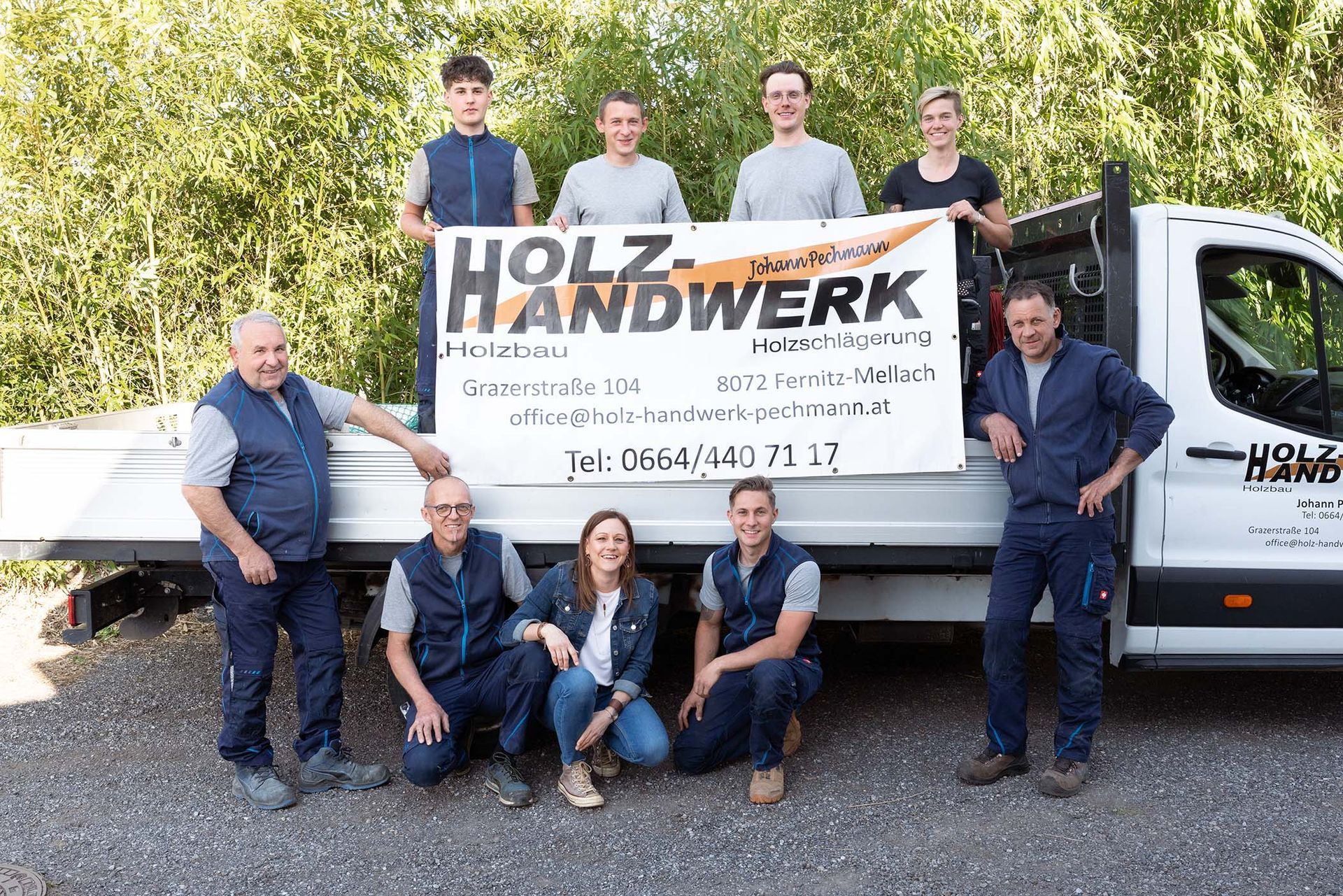 Das Team von Holz-Handwerk posiert vor einem Wagen für ein Foto.