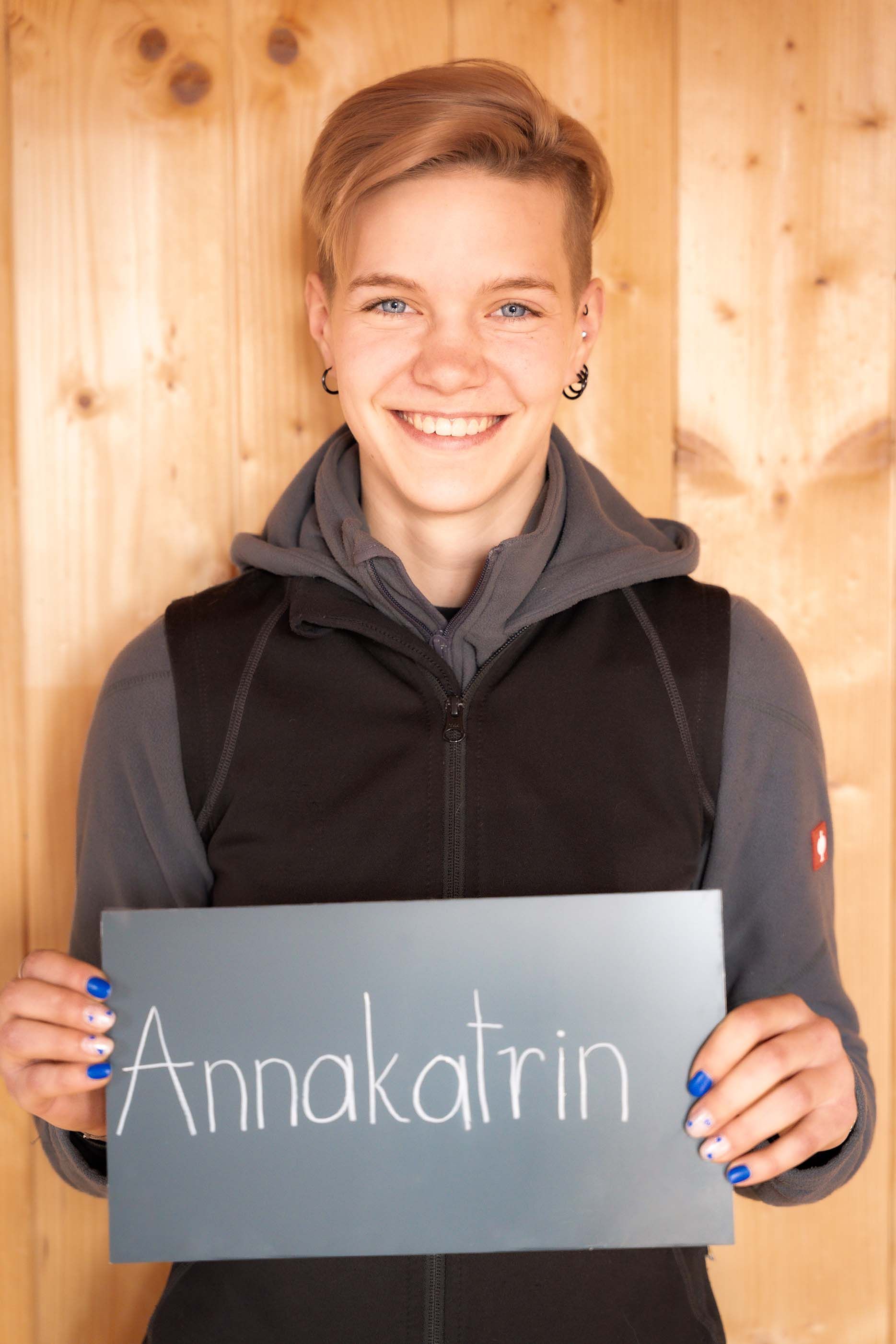 Eine junge Frau hält ein Schild mit der Aufschrift „Annakatrina“.