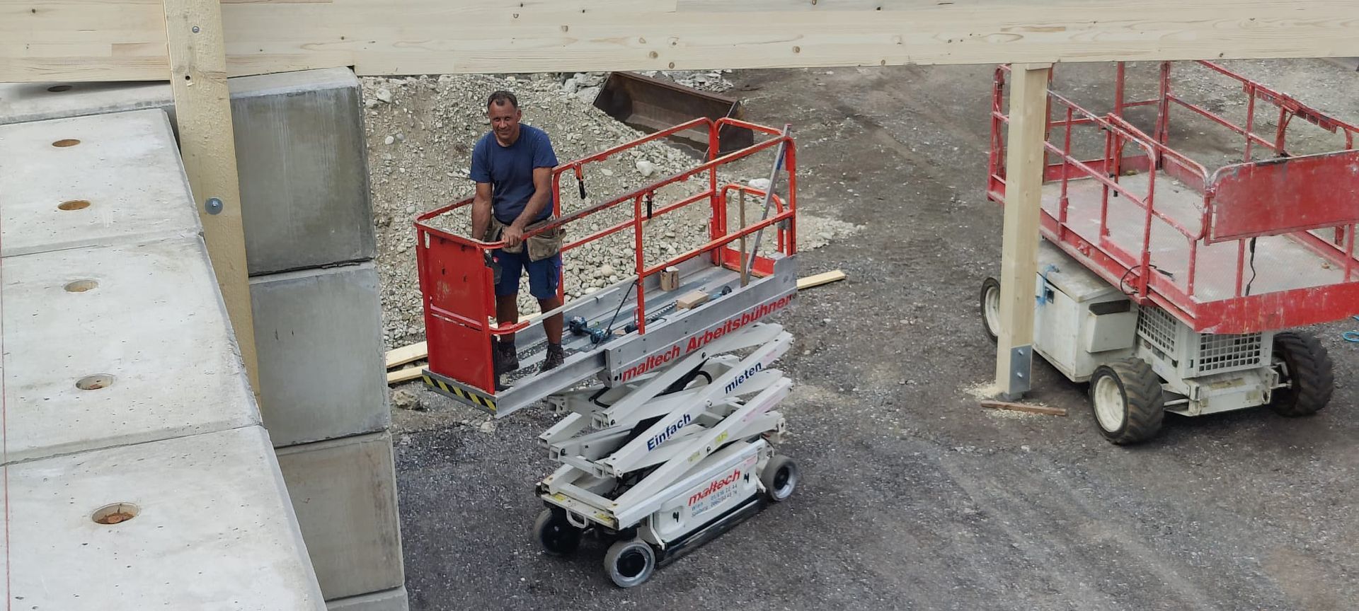 Ein Mann steht auf einer Baustelle auf einer Scherenbühne.