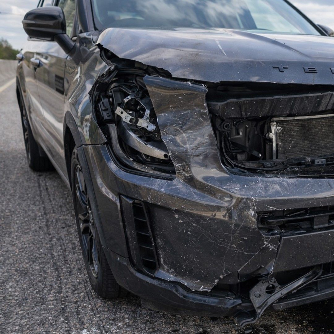 Front passenger side bumper of a black SUV on a Fort Worth highway is crumpled from car accident