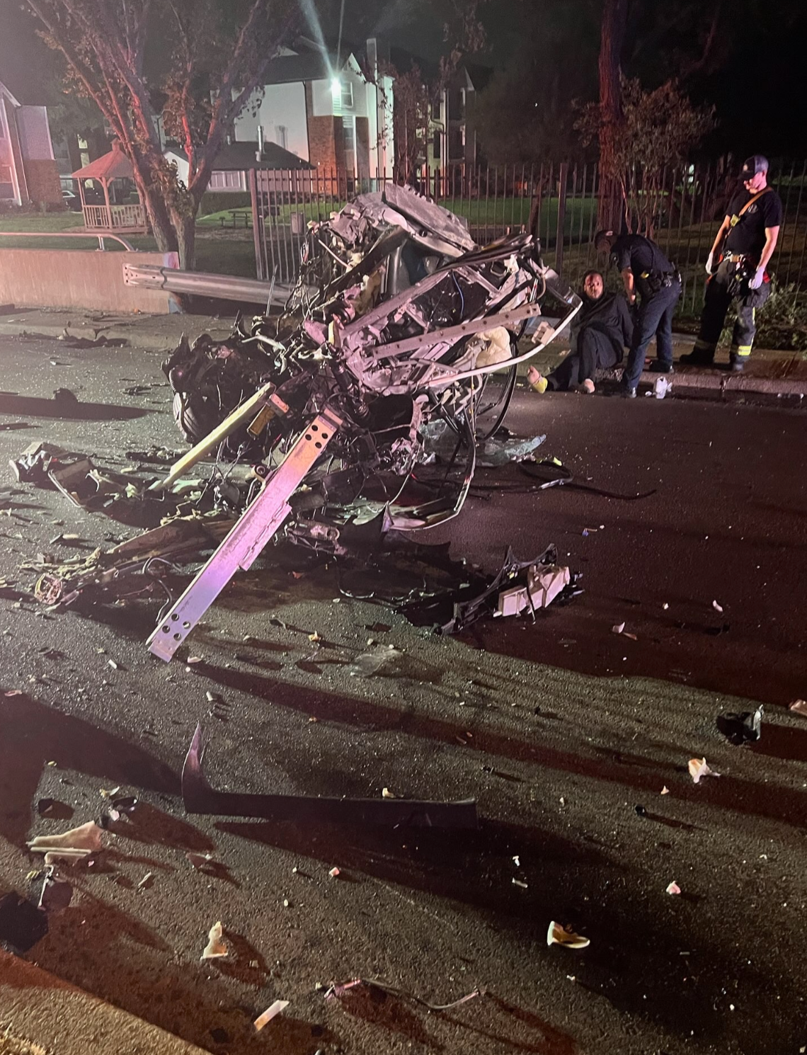 A car has crashed into a tree on the side of the road at night.