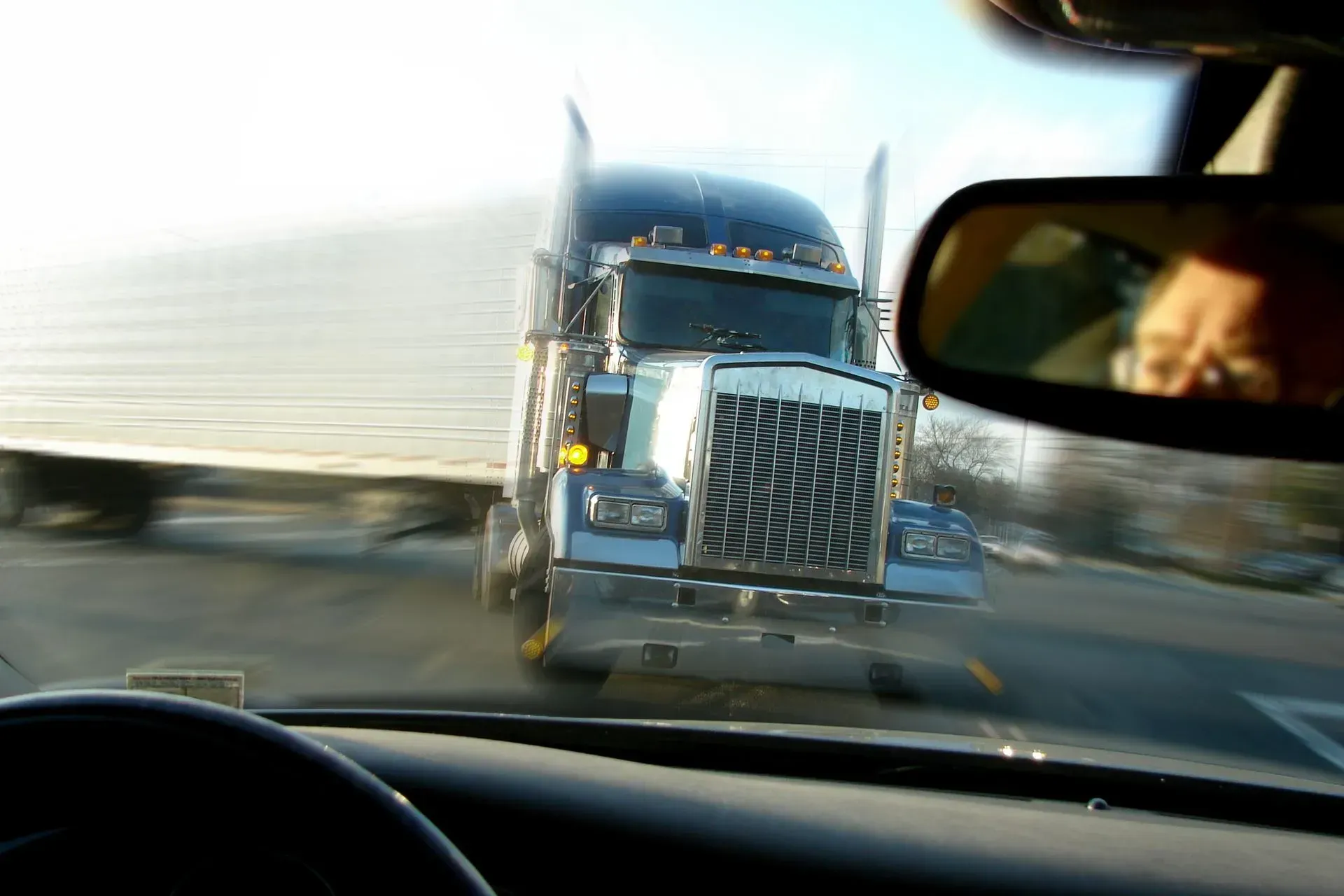 Semi truck heading straight for a passenger car on a highway.