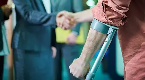 A man with crutches is shaking hands with a man in a suit.