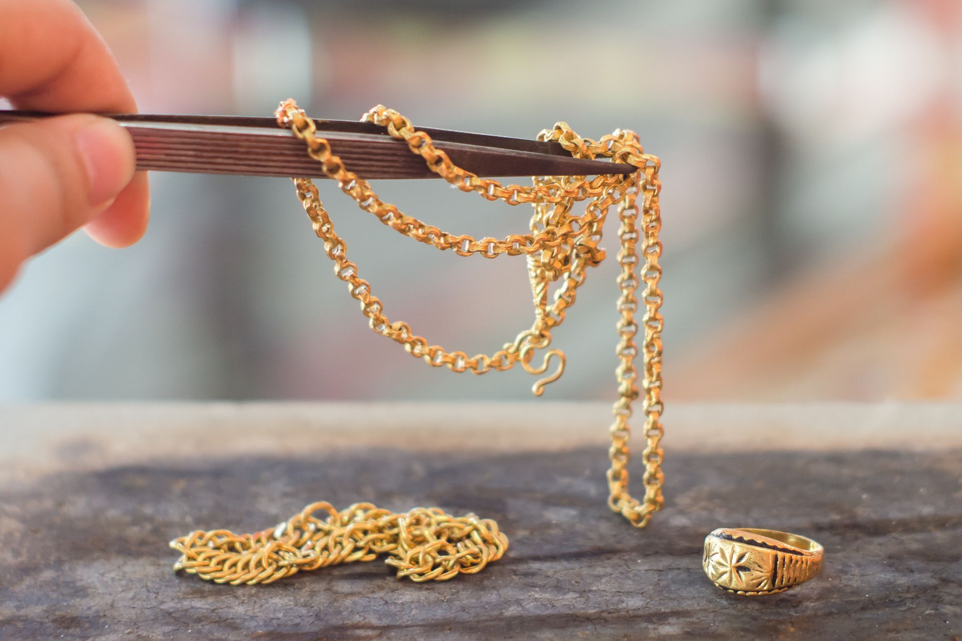 Pawn shop evaluating a gold chain and ring with tweezers for quick cash appraisal