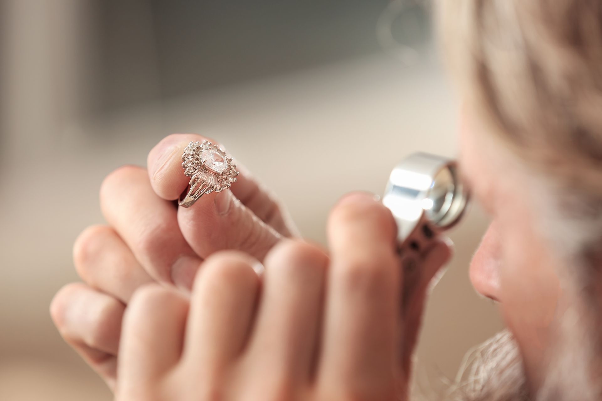 Person examining a ring with a magnifying glass. Person examining a ring with a magnifying glass.
