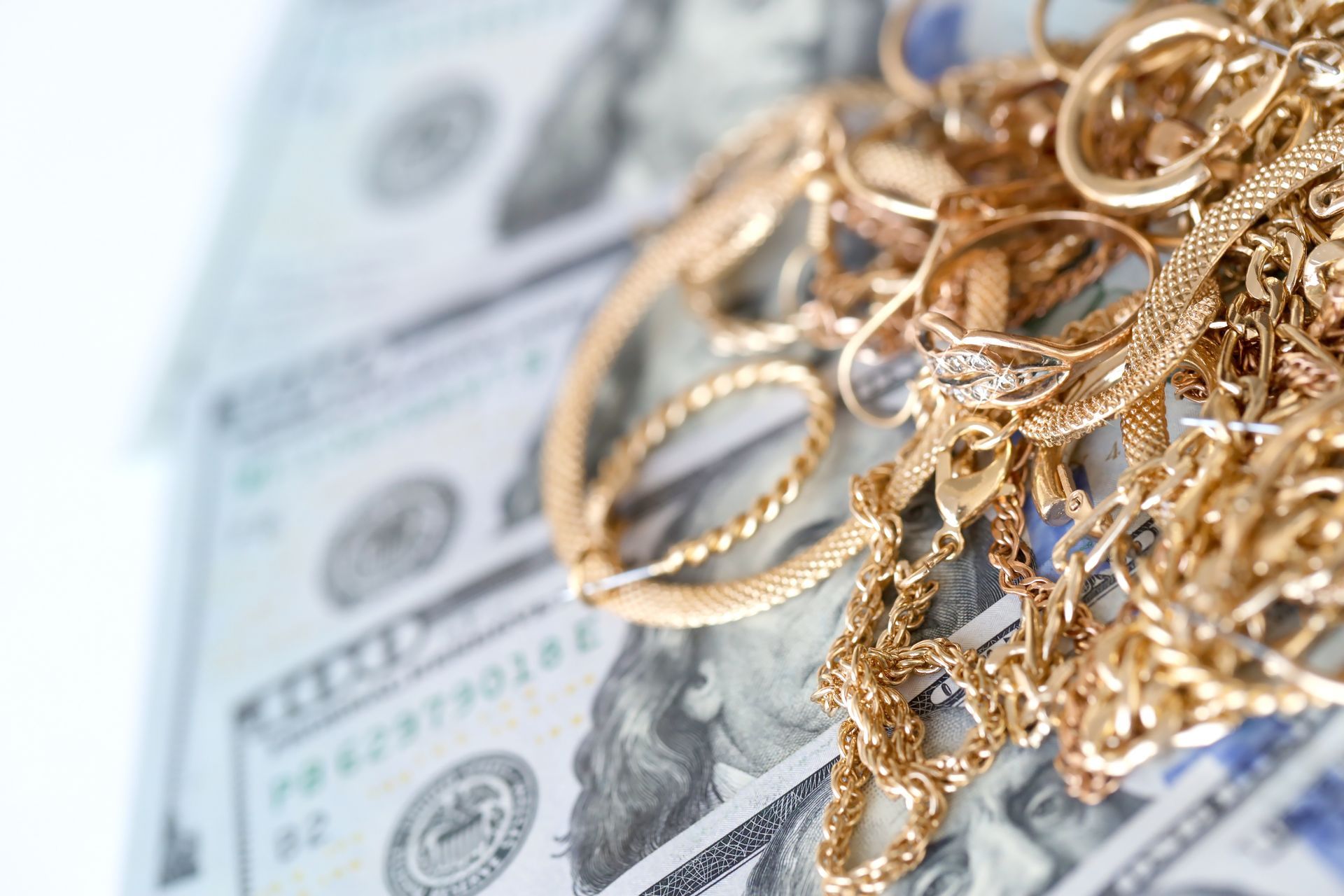 Gold jewelry piled on cash at a pawn shop counter. Gold jewelry piled on cash at a pawn shop counter.