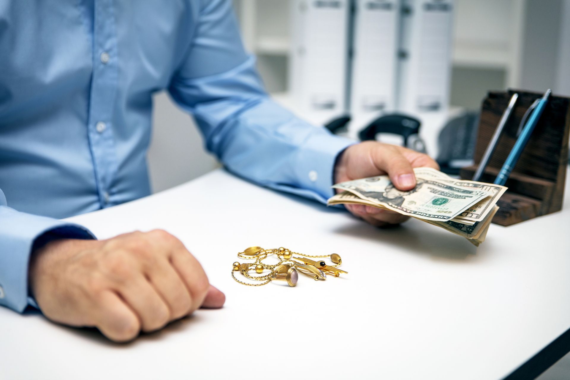 Cash offered for gold jewelry on a desk during professional gold buying and appraisal services.