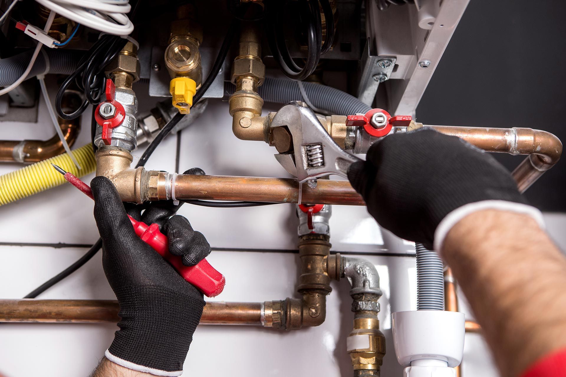 Plumbing repair on copper pipes using wrench and tool inside mechanical system unit service repairs.