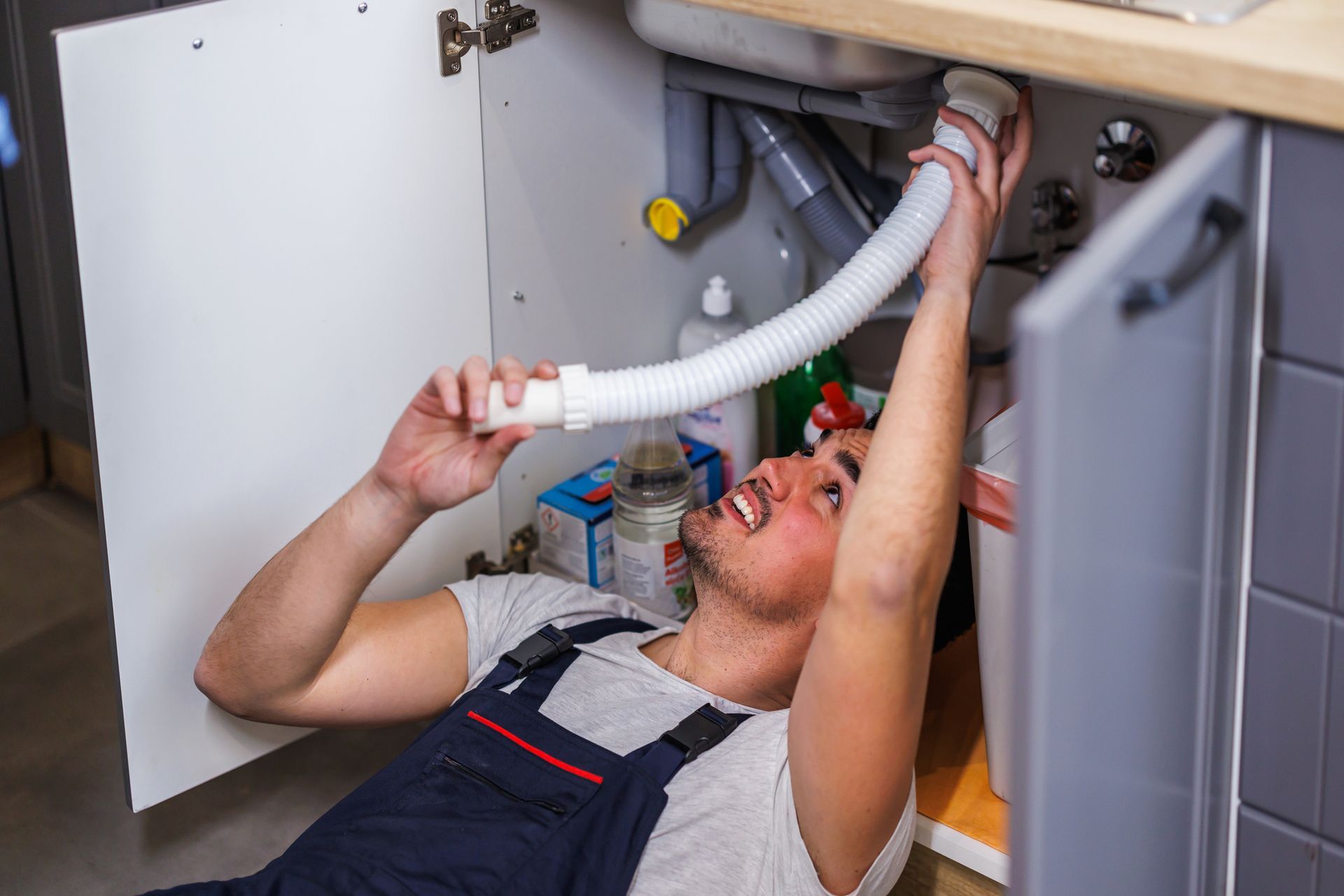 Skilled plumber repairing sink drain using professional tools with precision. Skilled plumber repairing sink drain using professional tools with precision.