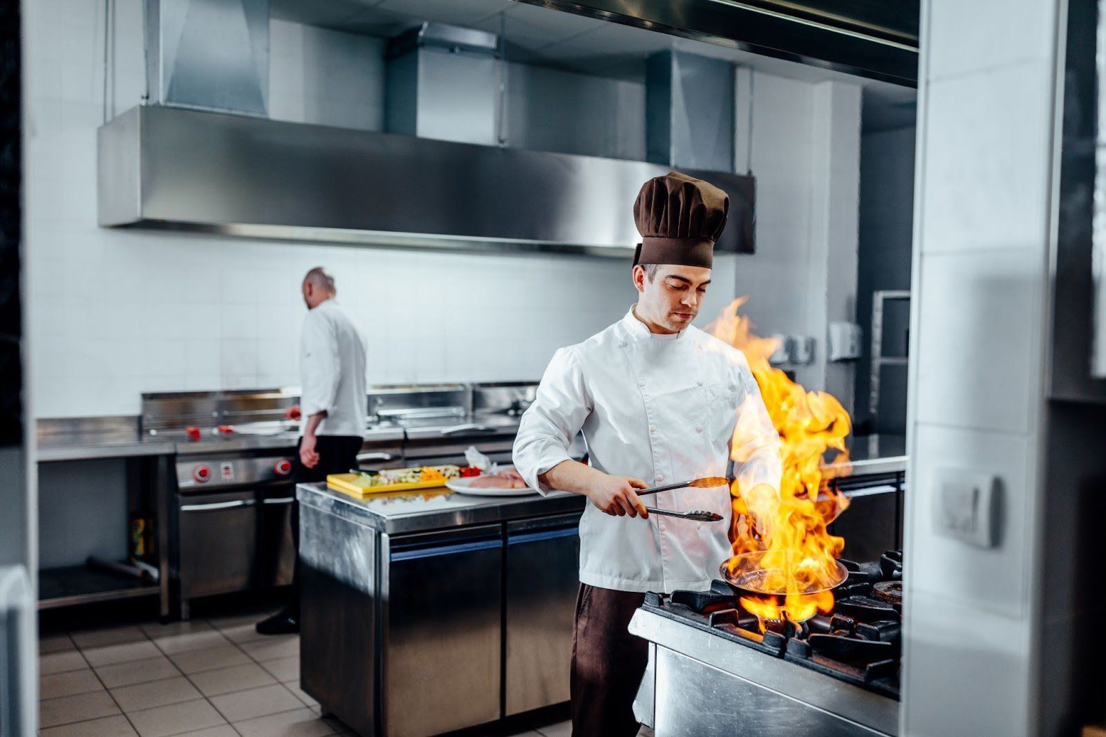Chef segurando panela pegando fogo em cozinha com cortina de ar industrial