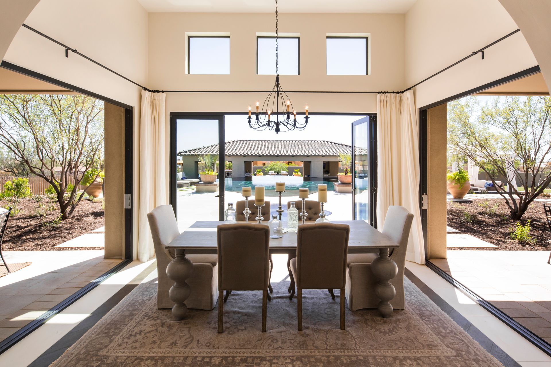 Elegant dining room with chandelier, open sliding doors, and patio view beyond modern table setting