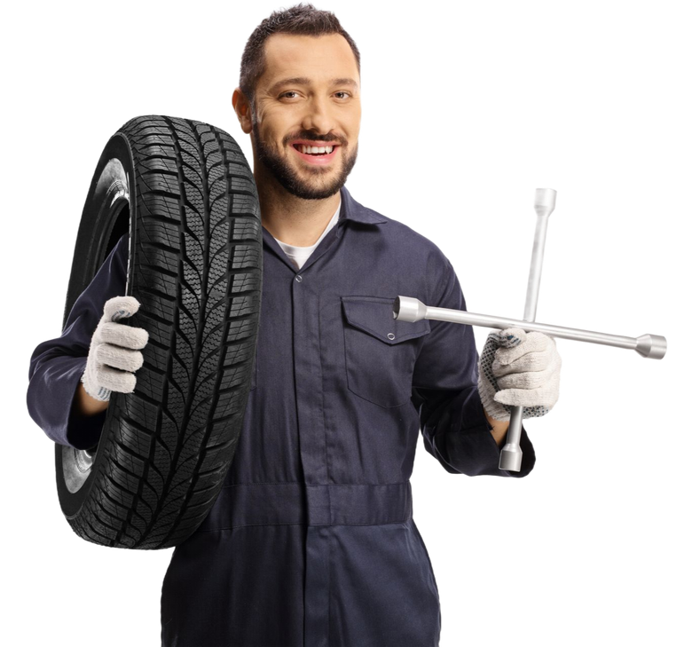 Mechanic holding a tire and tire iron, smiling in dark blue coveralls on a white background