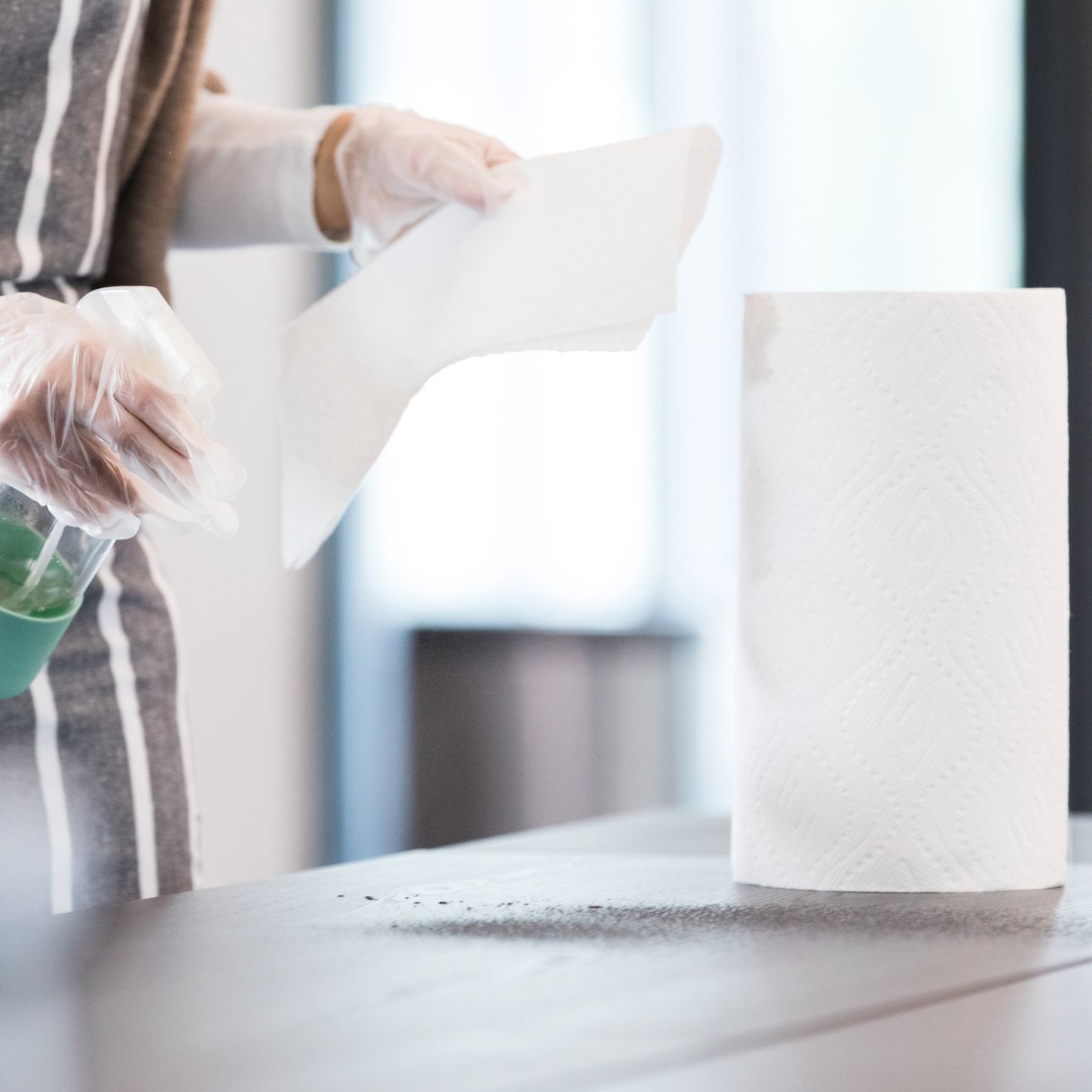 A person is holding a piece of paper next to a roll of paper towels.