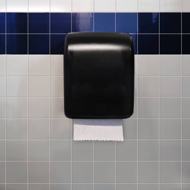 A black paper towel dispenser is hanging on a tiled wall.