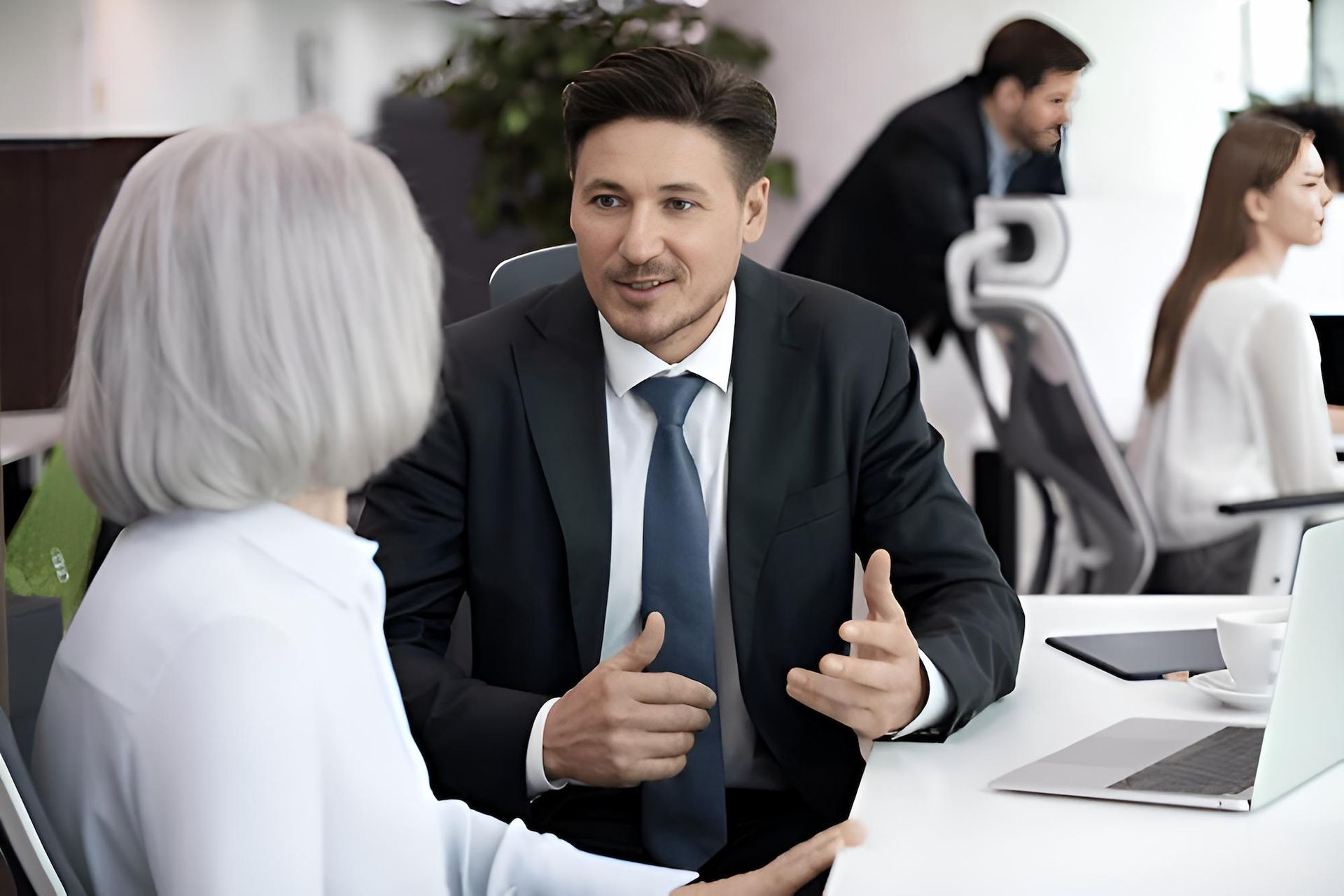A Man in a Suit and Tie is Talking to an Older Woman in an Office — O'Reilly & Sochacki Lawyers in Murwillumbah, NSW