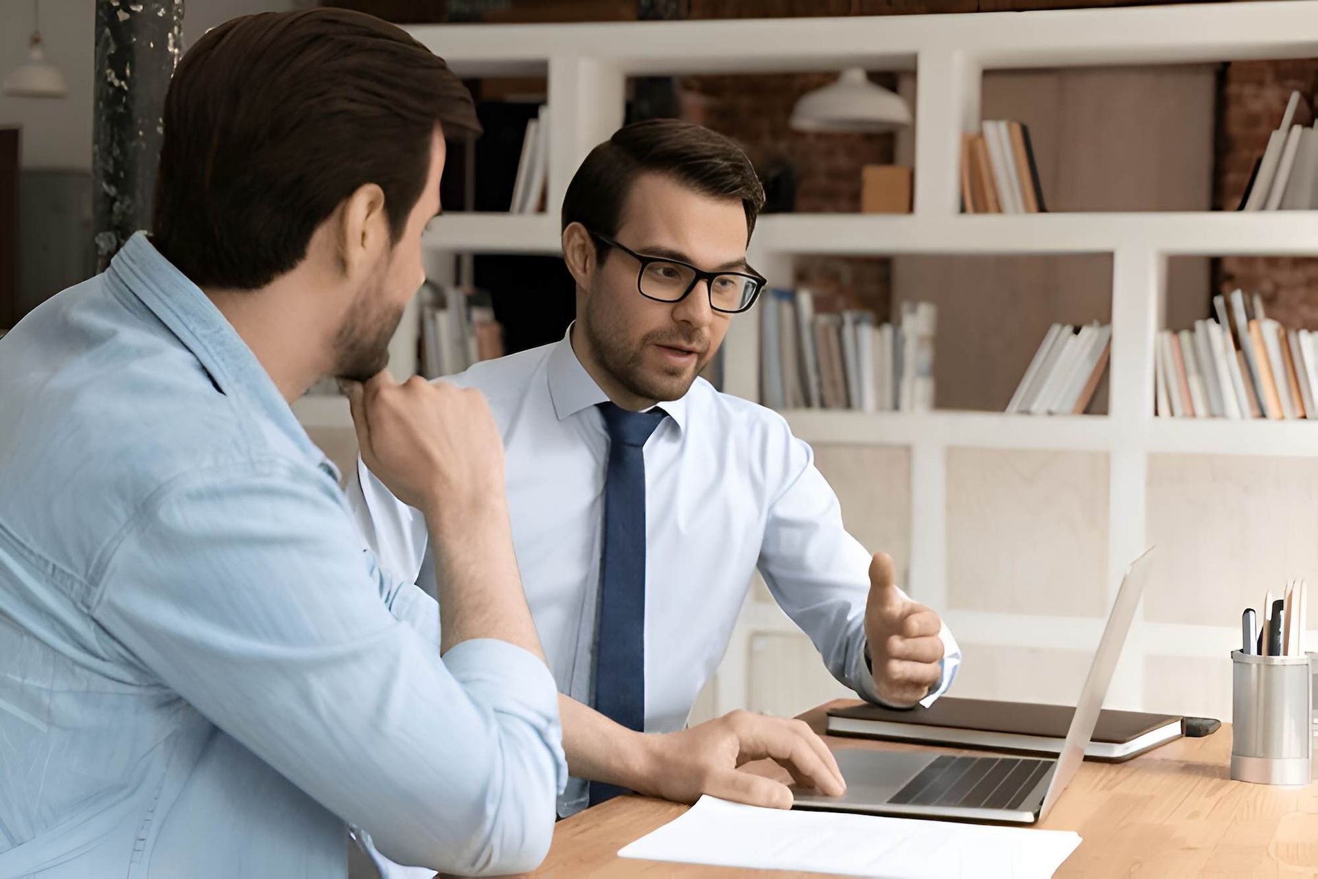 Two Men Are Sitting at a Table Looking at a Laptop Computer — O'Reilly & Sochacki Lawyers in Murwillumbah, NSW