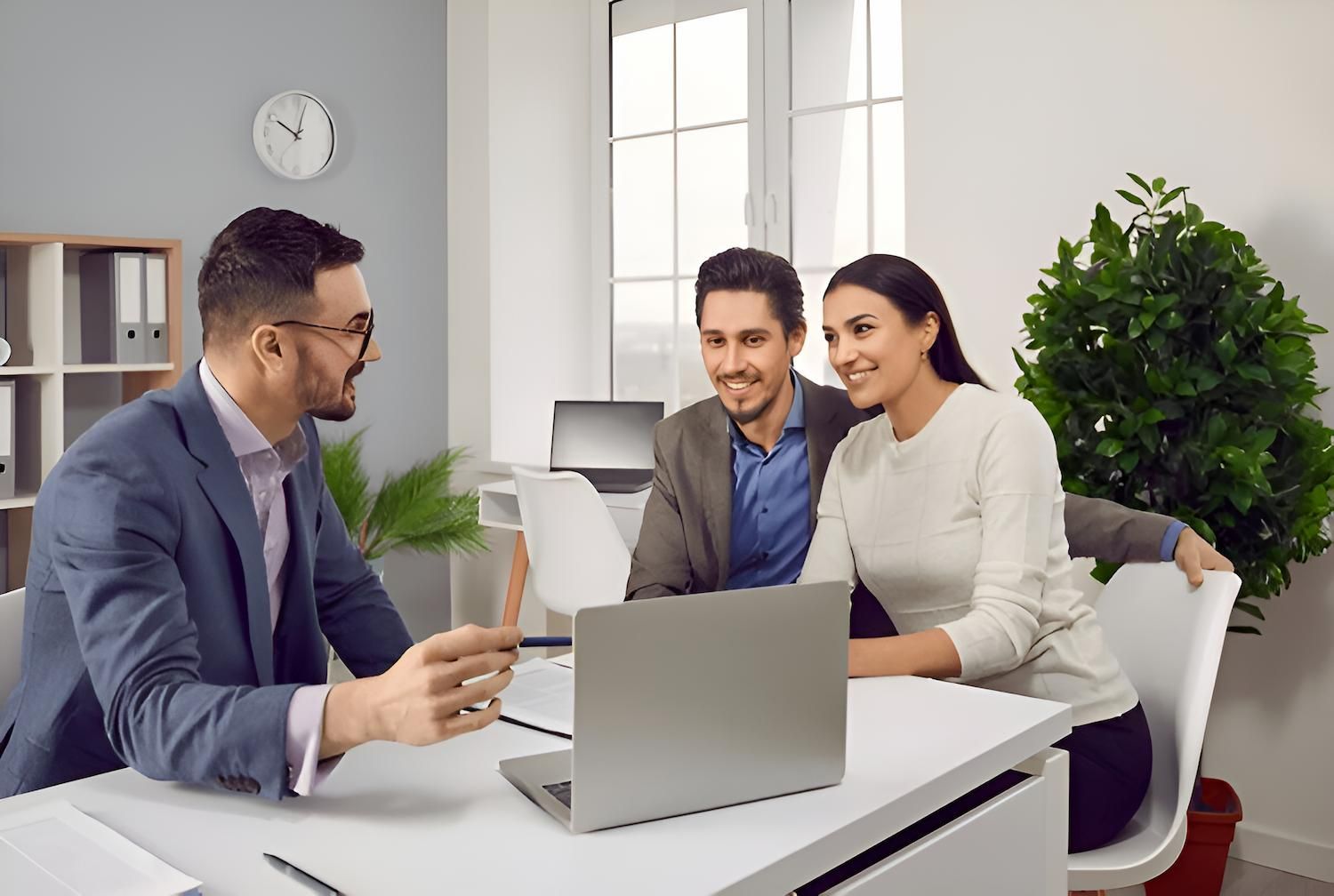 A Man is Talking to a Couple While Sitting at a Desk With a Laptop — O'Reilly & Sochacki Lawyers in Pottsville, NSW