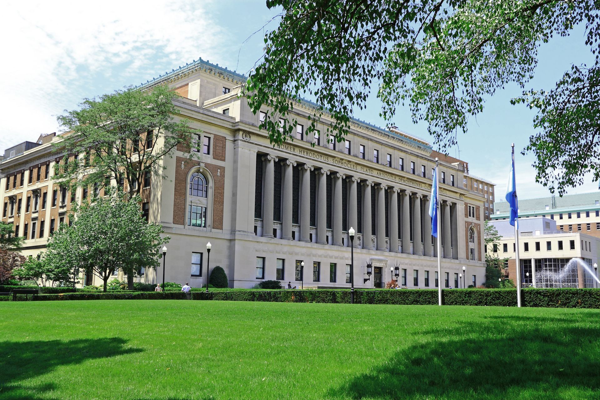 a large building with columns is surrounded by grass and trees