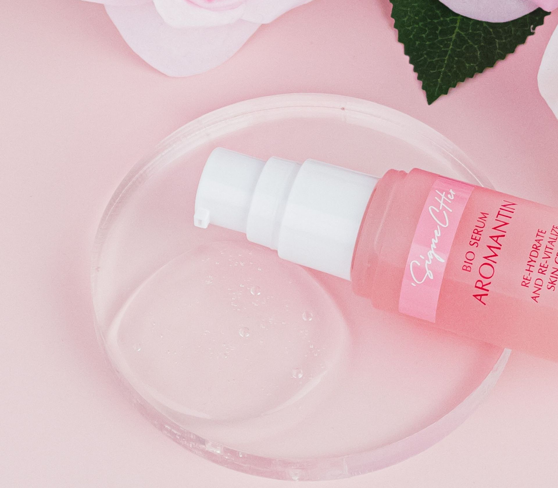 A pink bottle of aromatherapy is on a clear plate