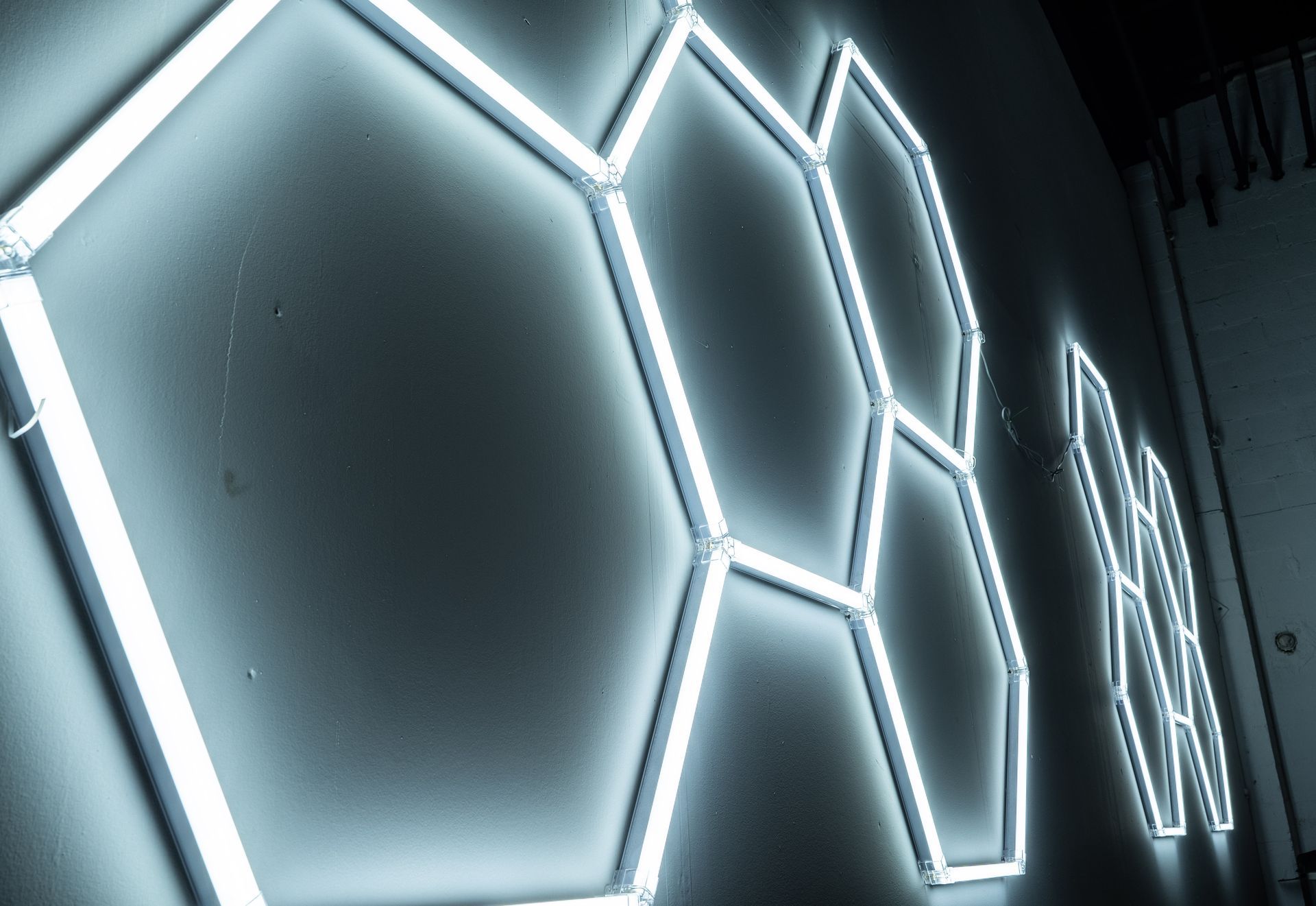 White glowing hexagonal neon lights on a gray wall.