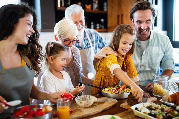 Family gathered around a dining table, serving food and smiling together