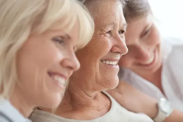 Three smiling people seated close together in a bright, softly lit setting