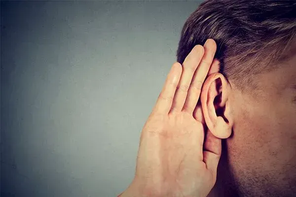 Hand cupped to ear beside a person’s head, suggesting listening or hearing difficulty