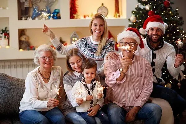 Family gathered on a couch, smiling with Christmas hats and Santa decor in a cozy living room
