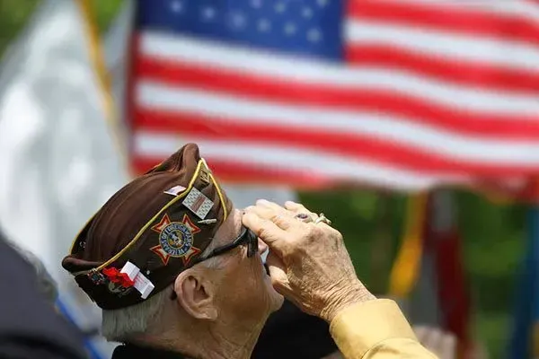 Veteran saluting in front of a blurred American flag