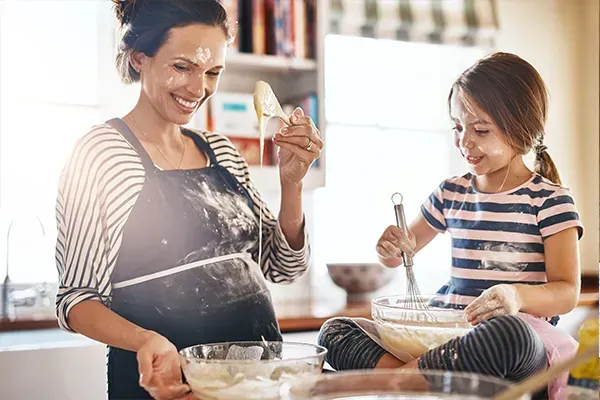 Two people baking in a bright kitchen, mixing batter and smiling at the counter.
