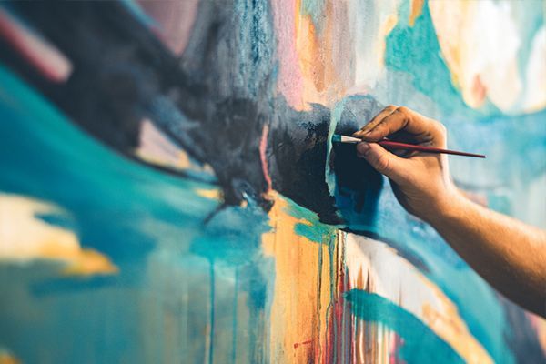 Hand painting a colorful abstract mural with a brush on a wall