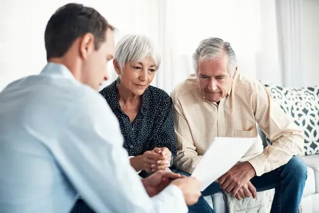 Three people reviewing documents together in a bright living room