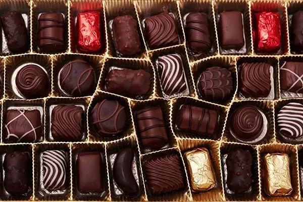 Assorted chocolates in a box, with dark, milk, and white striped pieces arranged in rows