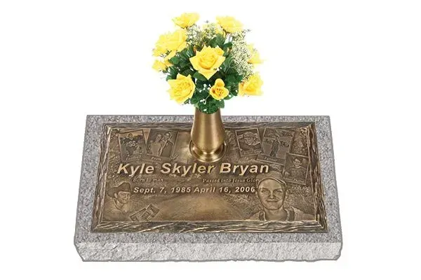 Memorial plaque with engraved name and yellow flowers in a bronze vase