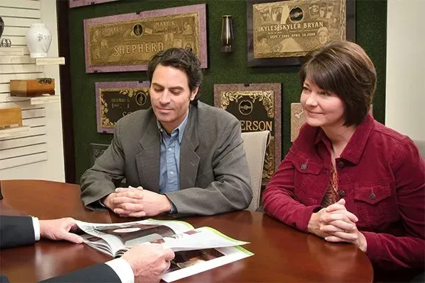 Two people seated at a table reviewing open brochures in a lobby or office setting